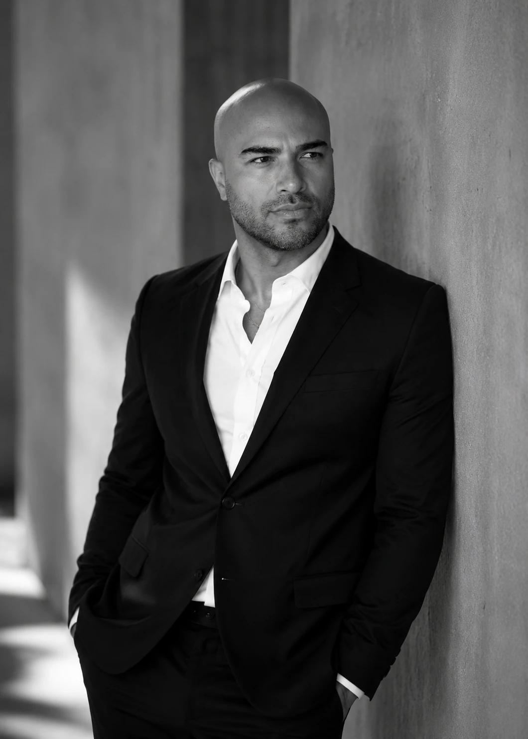Portrait of Clint Torres Jr.. OHO Hawaii. A black-and-white portrait in a tailored suit against an architectural backdrop.